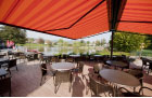 Image of folding-arm awnings fitted over seating area of lakeside restaurant.